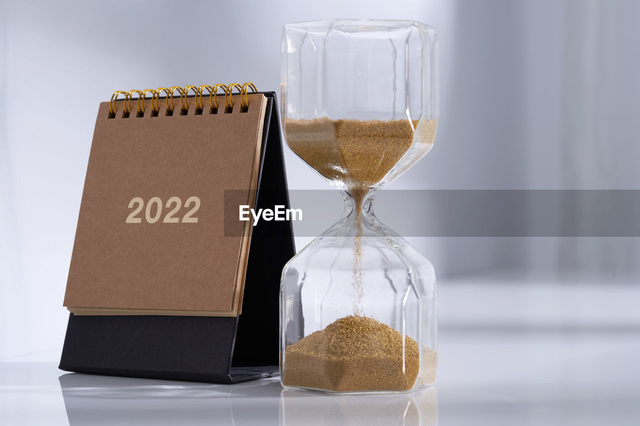 Hourglass with calendar on white desk close up. time concept