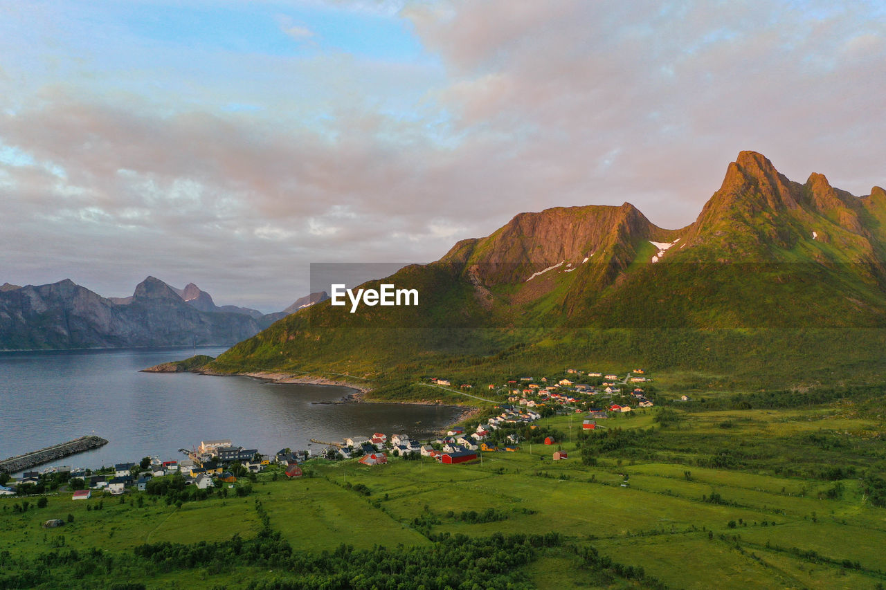 Mountain peaks and a small coastal village during sunset in senja island, norway