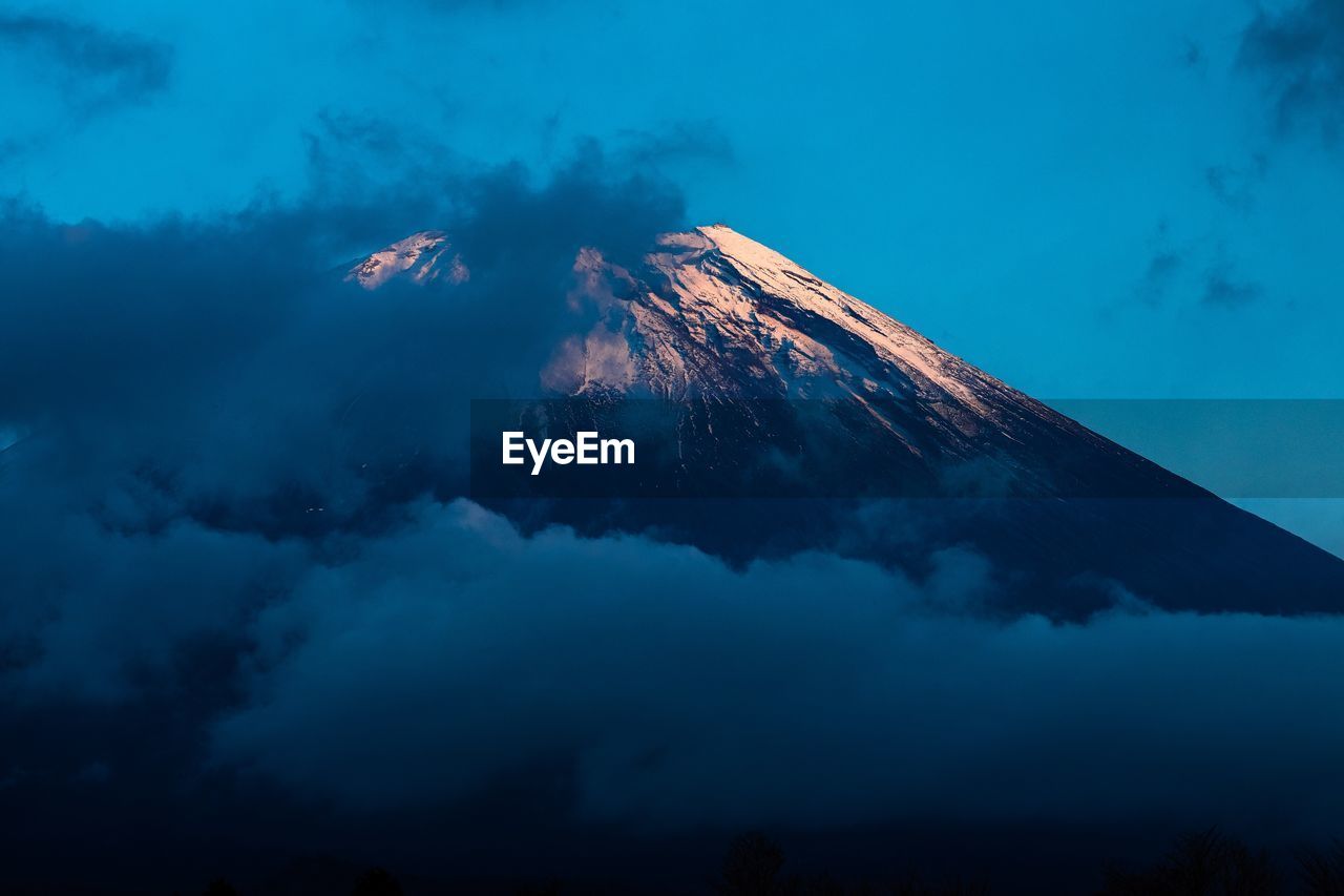 Low angle view of volcanic mountain against blue sky-fuji