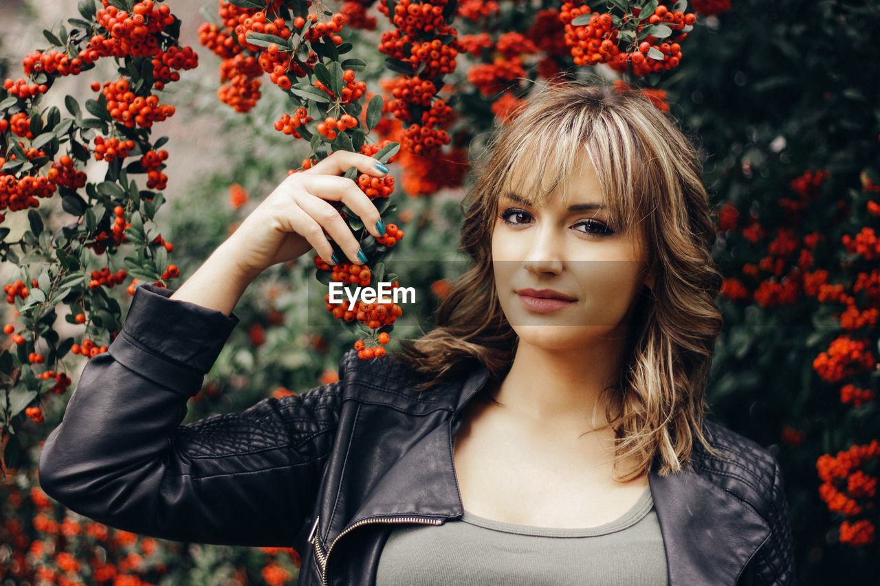 Portrait of young woman with fruits hanging on branch