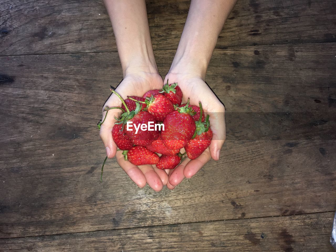 Cropped hands of woman holding strawberries at table