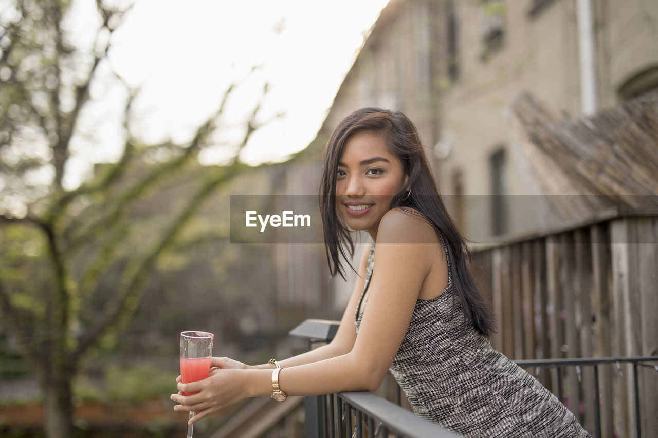 Young woman with a cocktail on her balcony