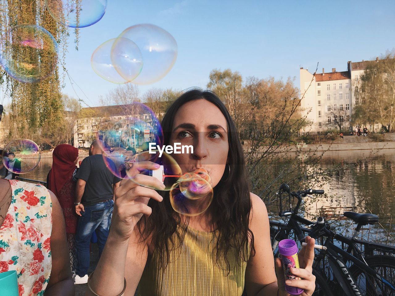 Portrait of young woman with bubbles against sky