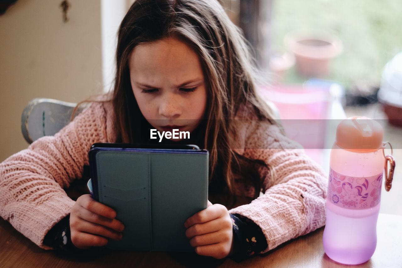 Close-up of girl using digital tablet on table at home