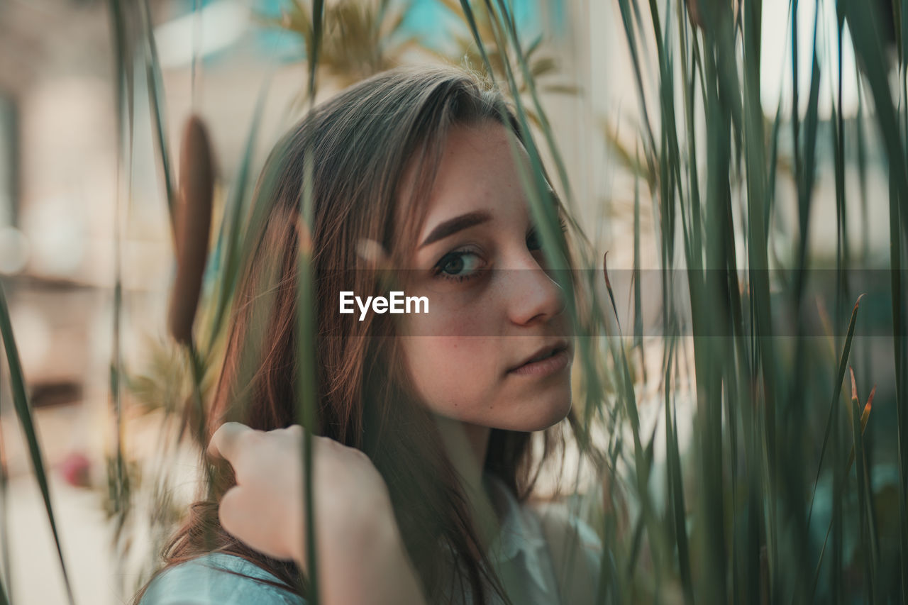 Close-up portrait of young woman standing by plants