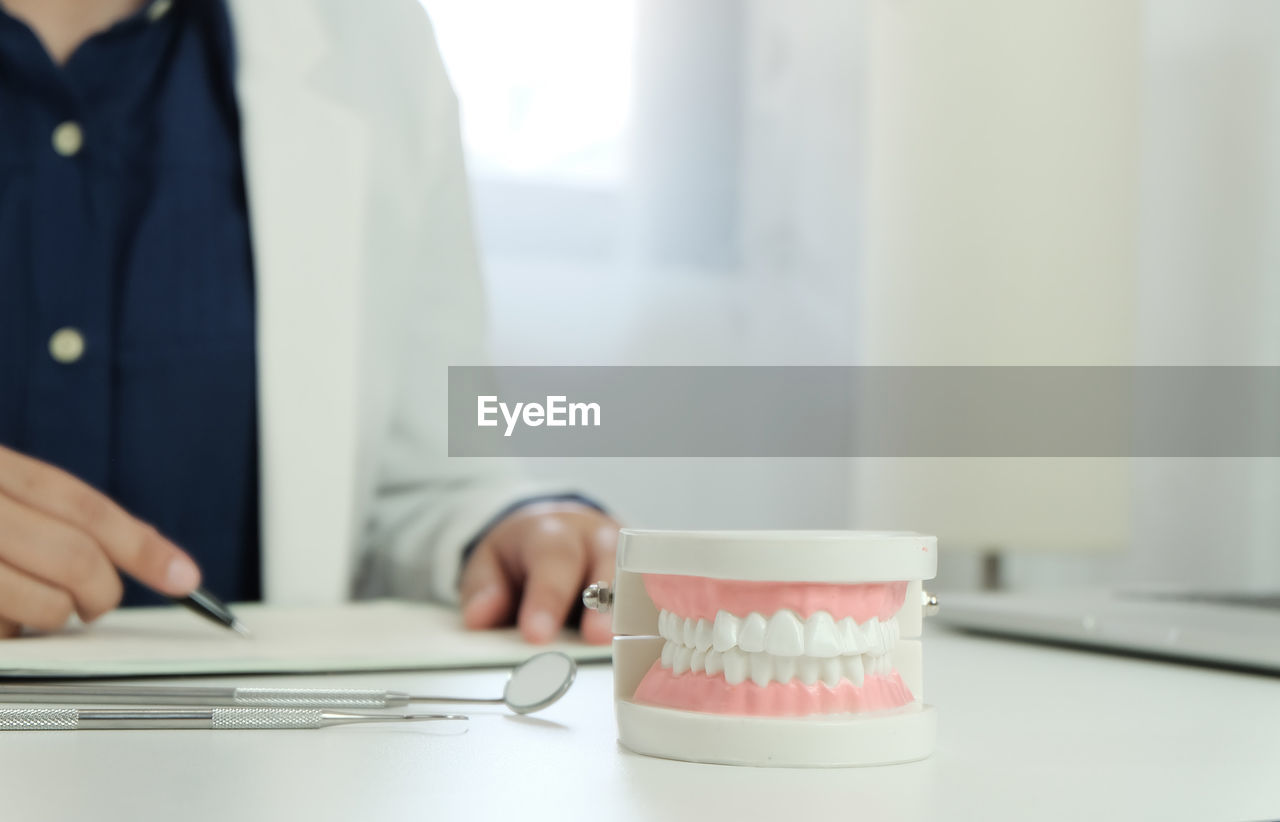 Midsection of dentist working with dentures in foreground at desk