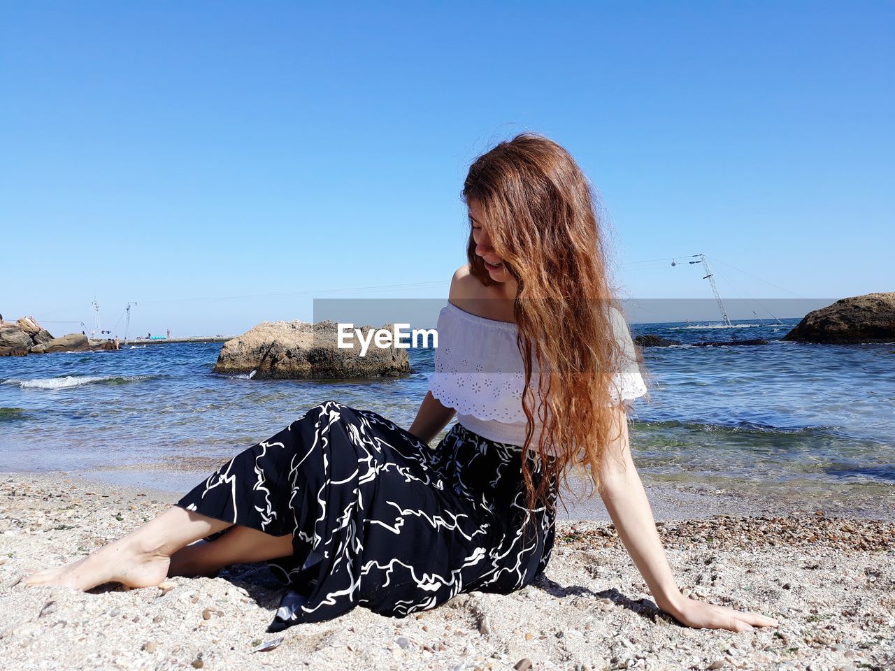 Young woman at beach against clear sky