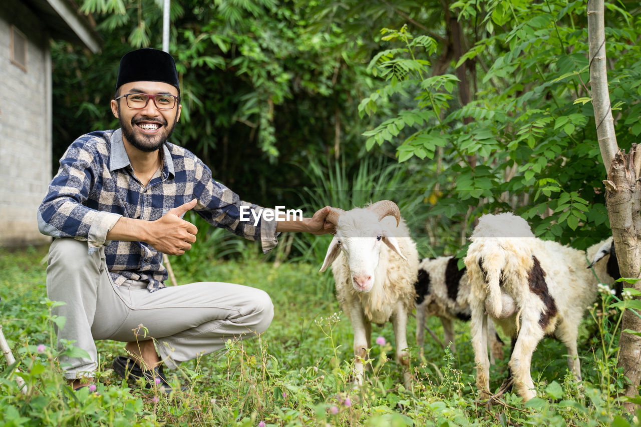 portrait of man with goat on grassy field
