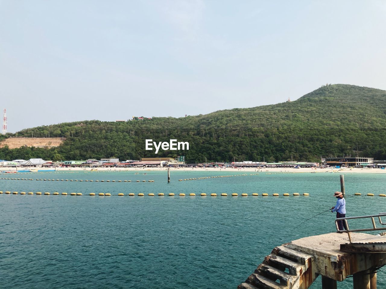 MAN ON SEA BY MOUNTAINS AGAINST SKY