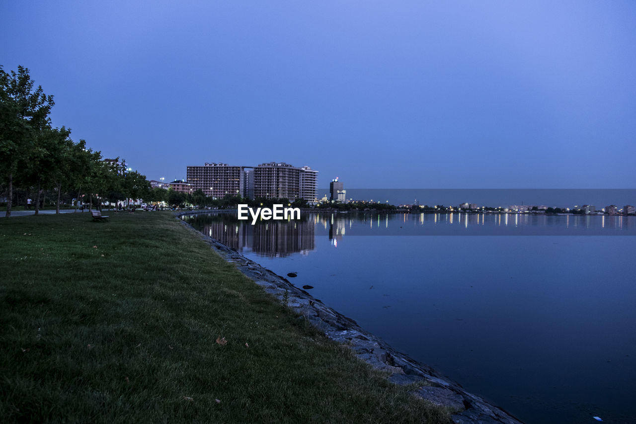 SCENIC VIEW OF RIVER BY BUILDINGS AGAINST CLEAR SKY