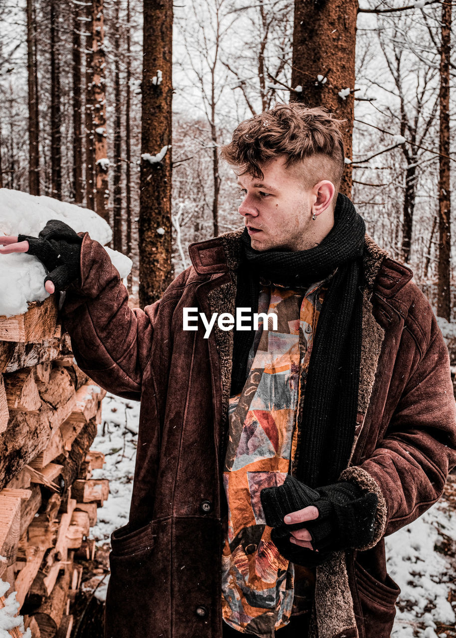 Young man standing by tree during winter