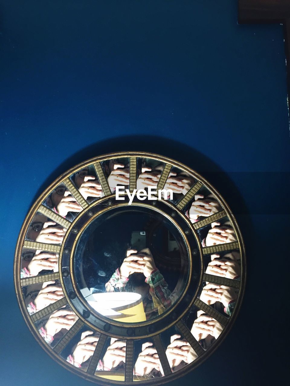 Reflection of person photographing on mirrors mounted on blue wall