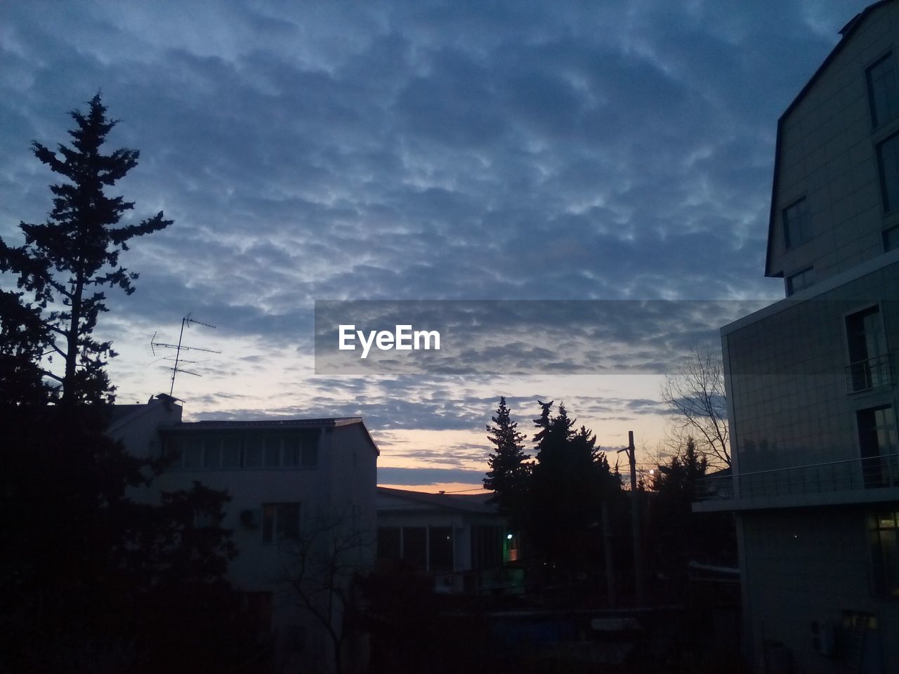 Silhouette of apartment building against cloudy sky