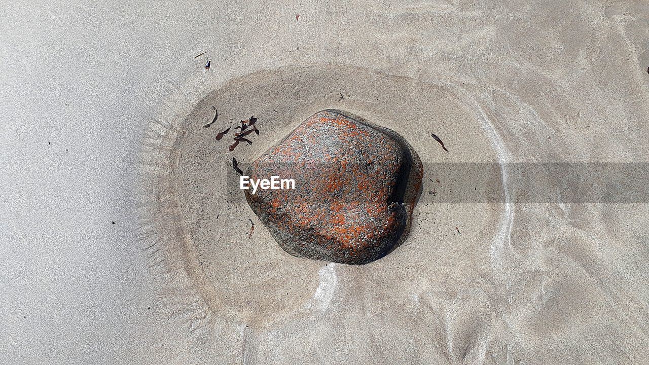 DIRECTLY ABOVE SHOT OF RUSTY METAL ON SAND