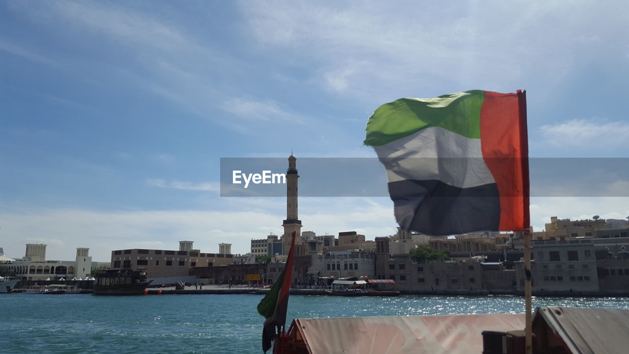 Panoramic view of cityscape against sky with fluttering uae flag