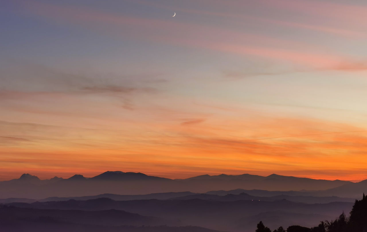 Scenic view of silhouette mountains against orange sky