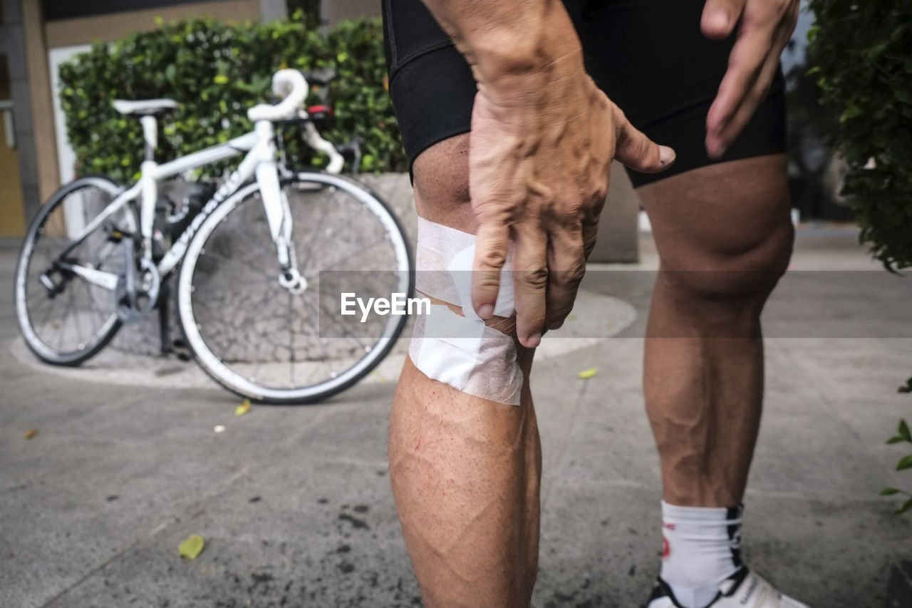 Low section of man with bandages on knee at footpath