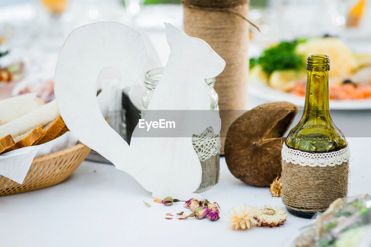 Holiday table decorations made of wooden squirrel figurines, flowers and bottles. 