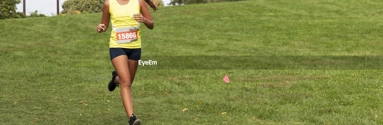 grass, running, sports, person, one person, plant, lifestyles, nature, recreation, day, exercising, sports clothing, motion, green, long distance running, athlete, shorts, leisure activity, track and field event, human leg, vitality, women, clothing, cross country running, adult, young adult, outdoors, race, field, casual clothing, on the move, endurance sports, competition, sunlight, full length, land, activity, front view, shoe, limb, running shorts, jogging, determination, athleticism