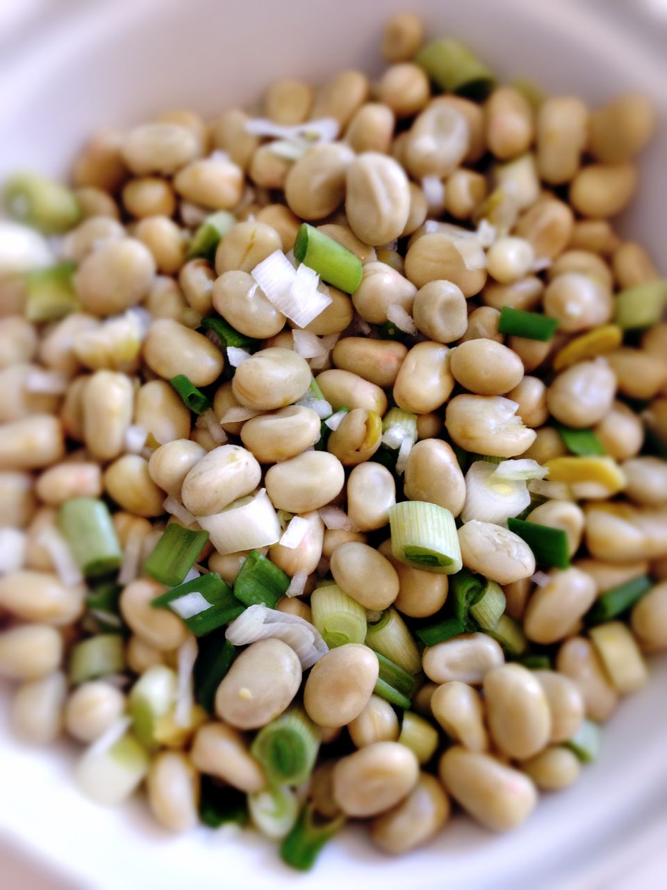 High angle view of beans and spring onions in plate