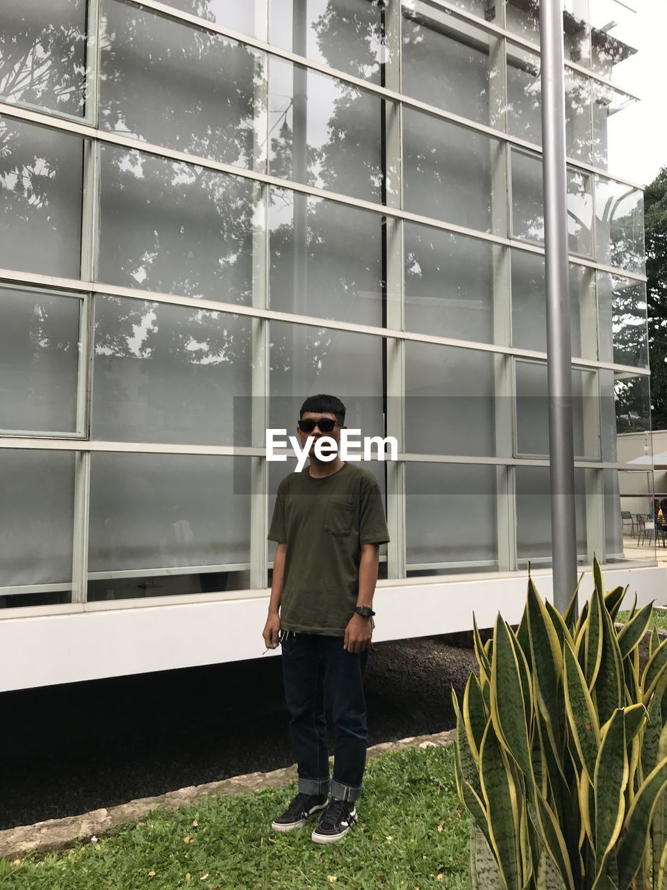 Full length of young man standing against glass building