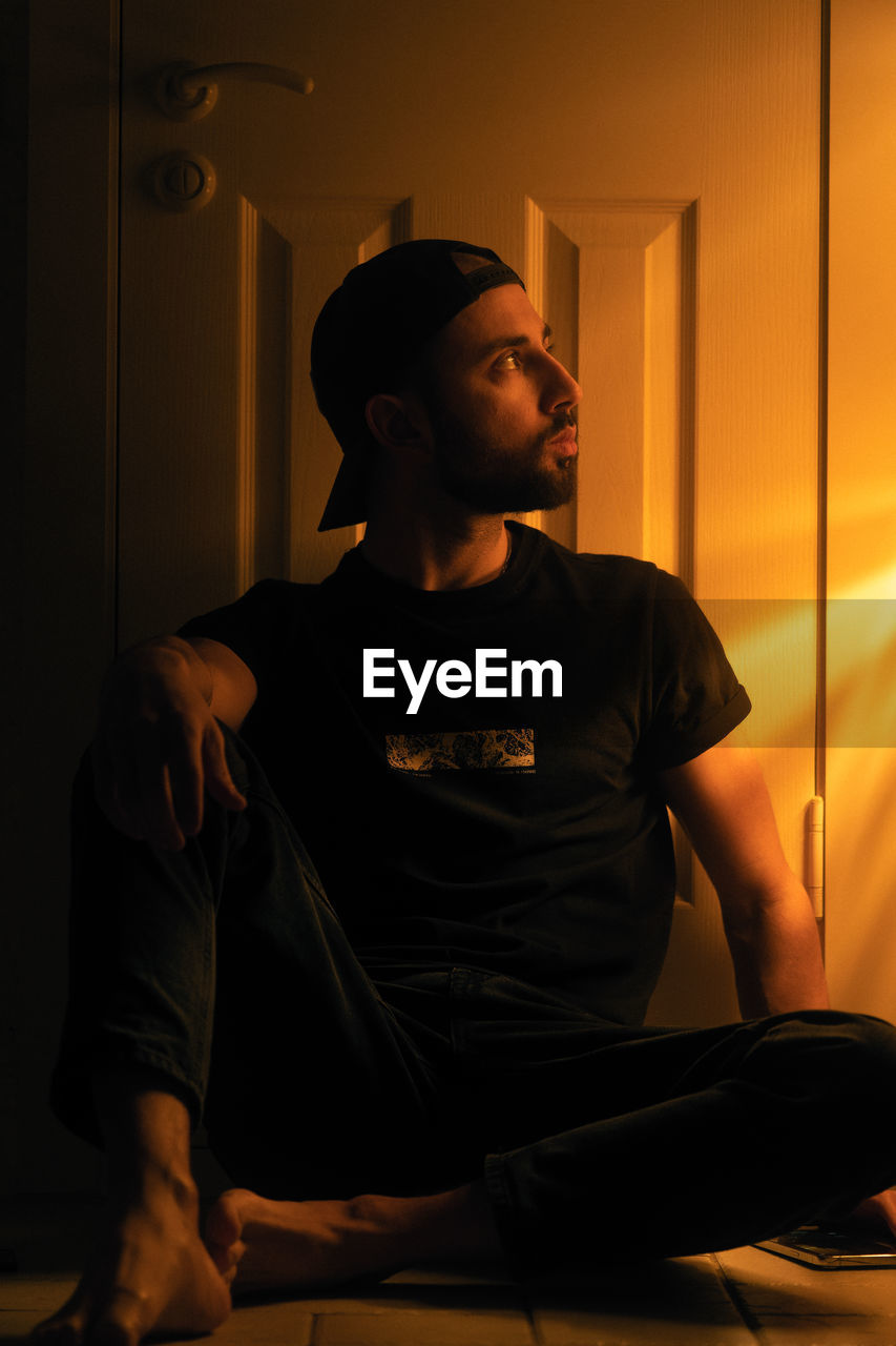 Young man looking away while sitting at home