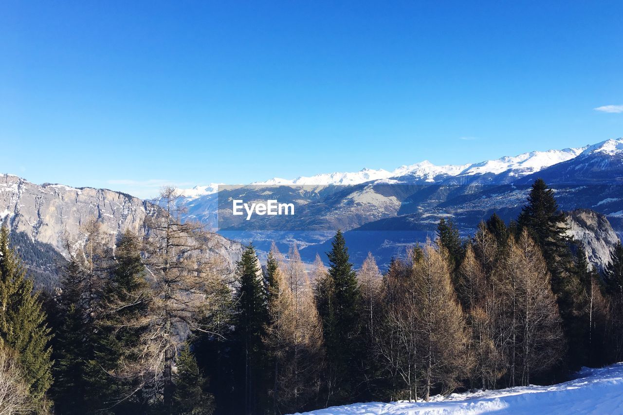 Scenic view of snowcapped mountains against clear blue sky