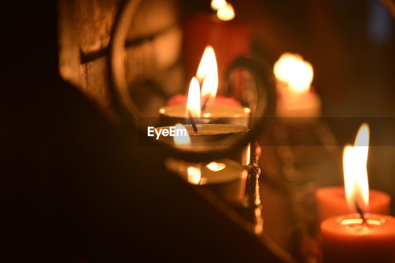 CLOSE-UP OF LIT CANDLES IN DARK