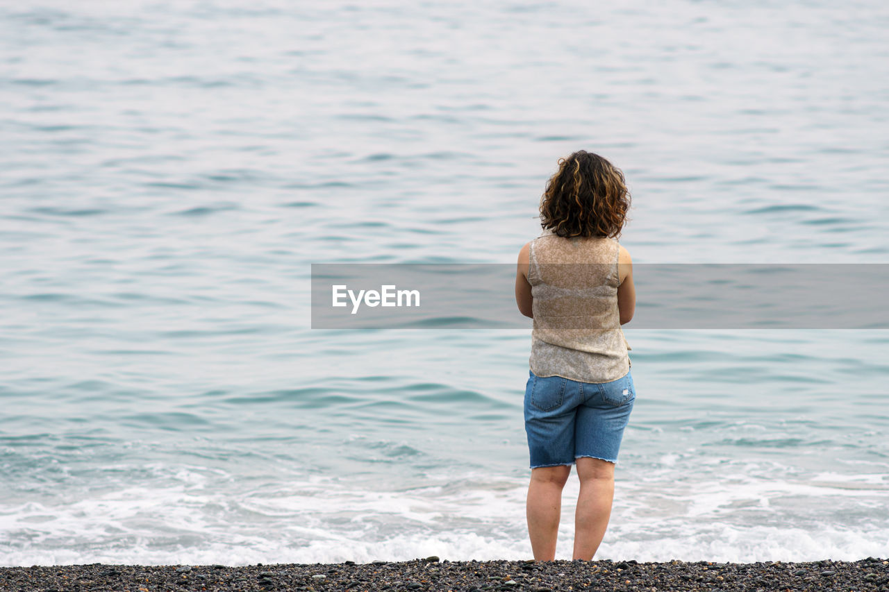 Rear view of woman standing at beach