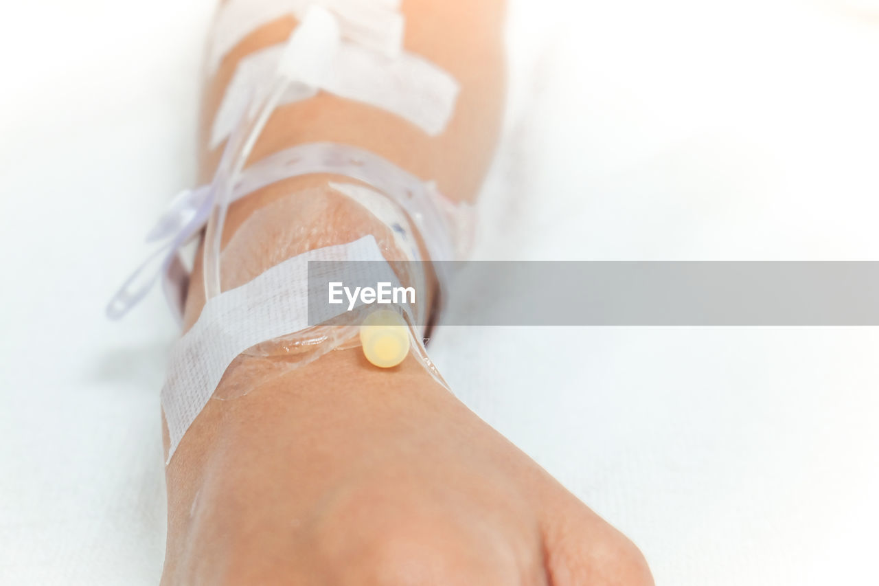 Cropped hand of patient on bed in hospital