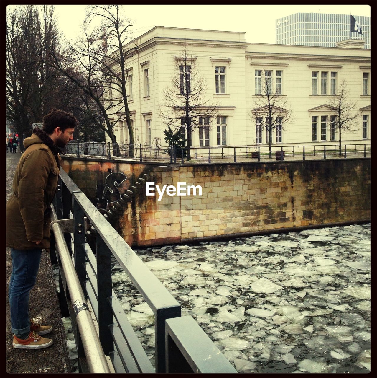 Full length side view of young man looking at frozen canal
