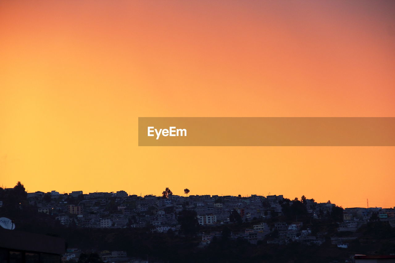 Buildings on mountain against clear sky during sunset