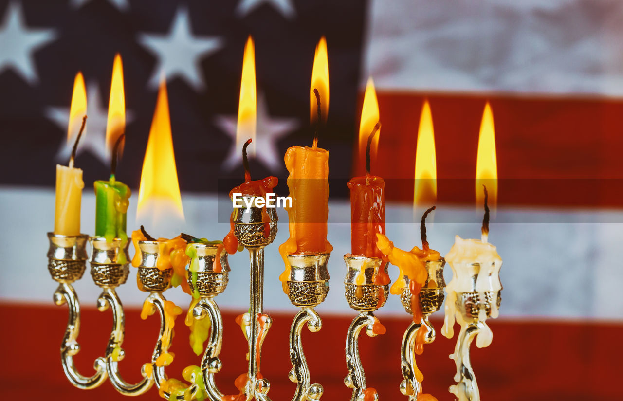 Close-up of illuminated candles on menorah against american flag