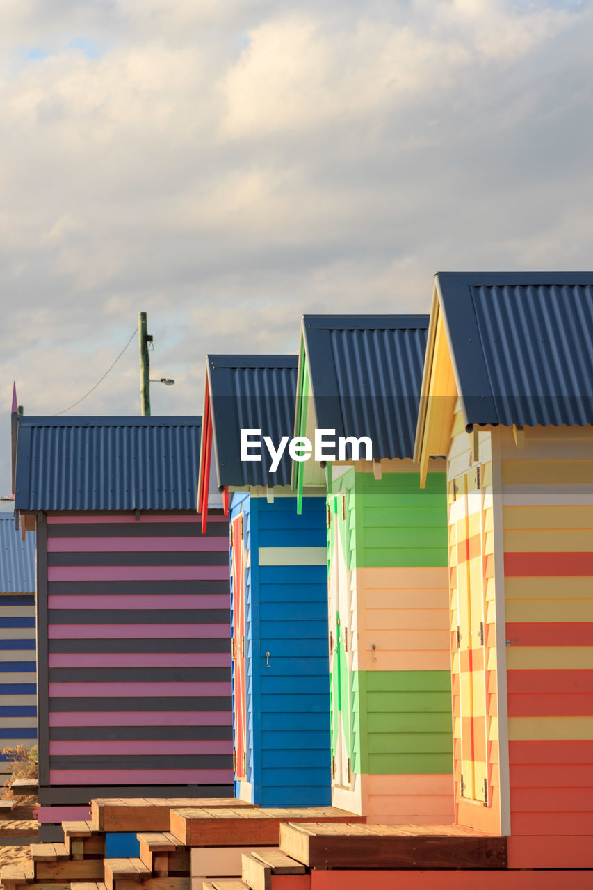 Low angle view of multi colored beach huts against sky