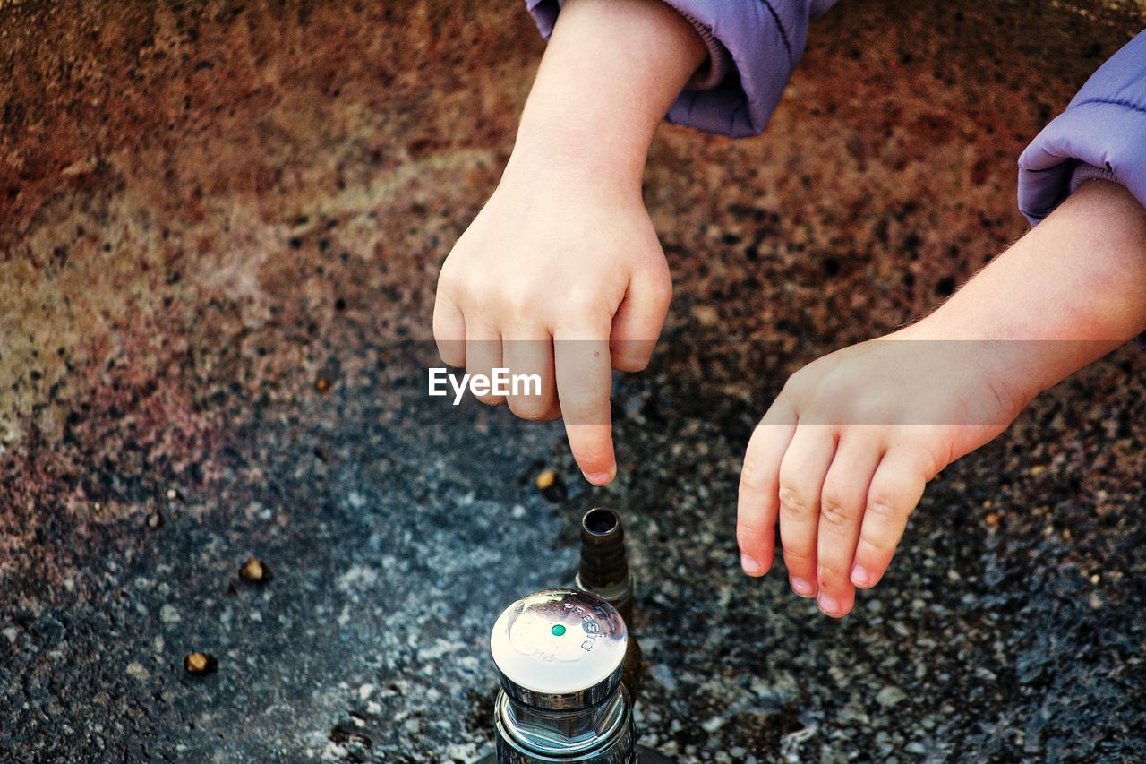 Cropped hands of child playing with container outdoors