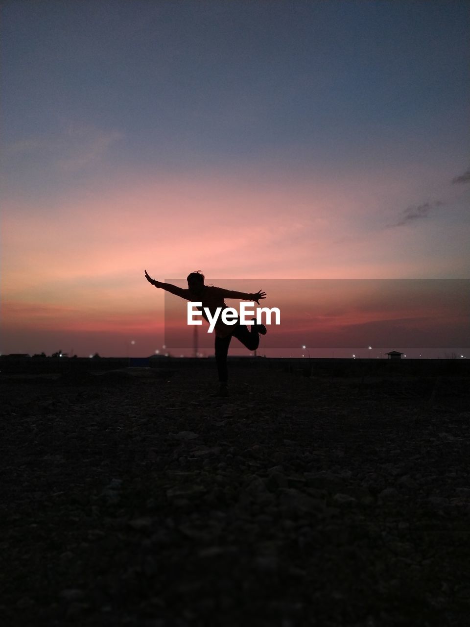 SILHOUETTE MAN STANDING ON FIELD AGAINST ORANGE SKY