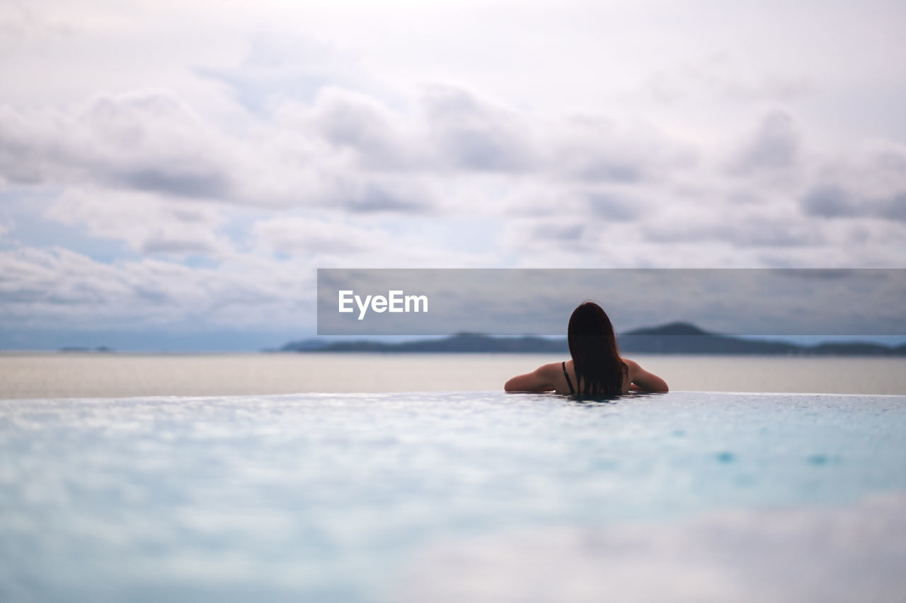 cropped image of man swimming in sea against sky