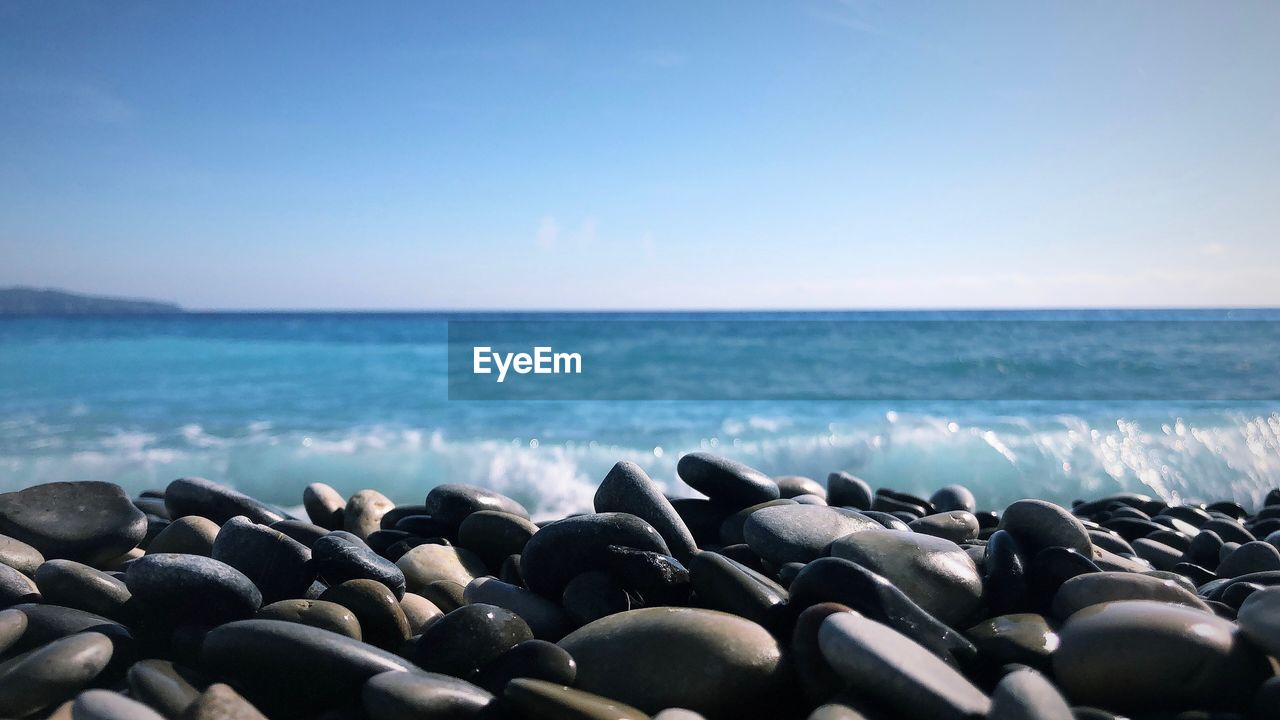 ROCKS ON BEACH AGAINST CLEAR SKY