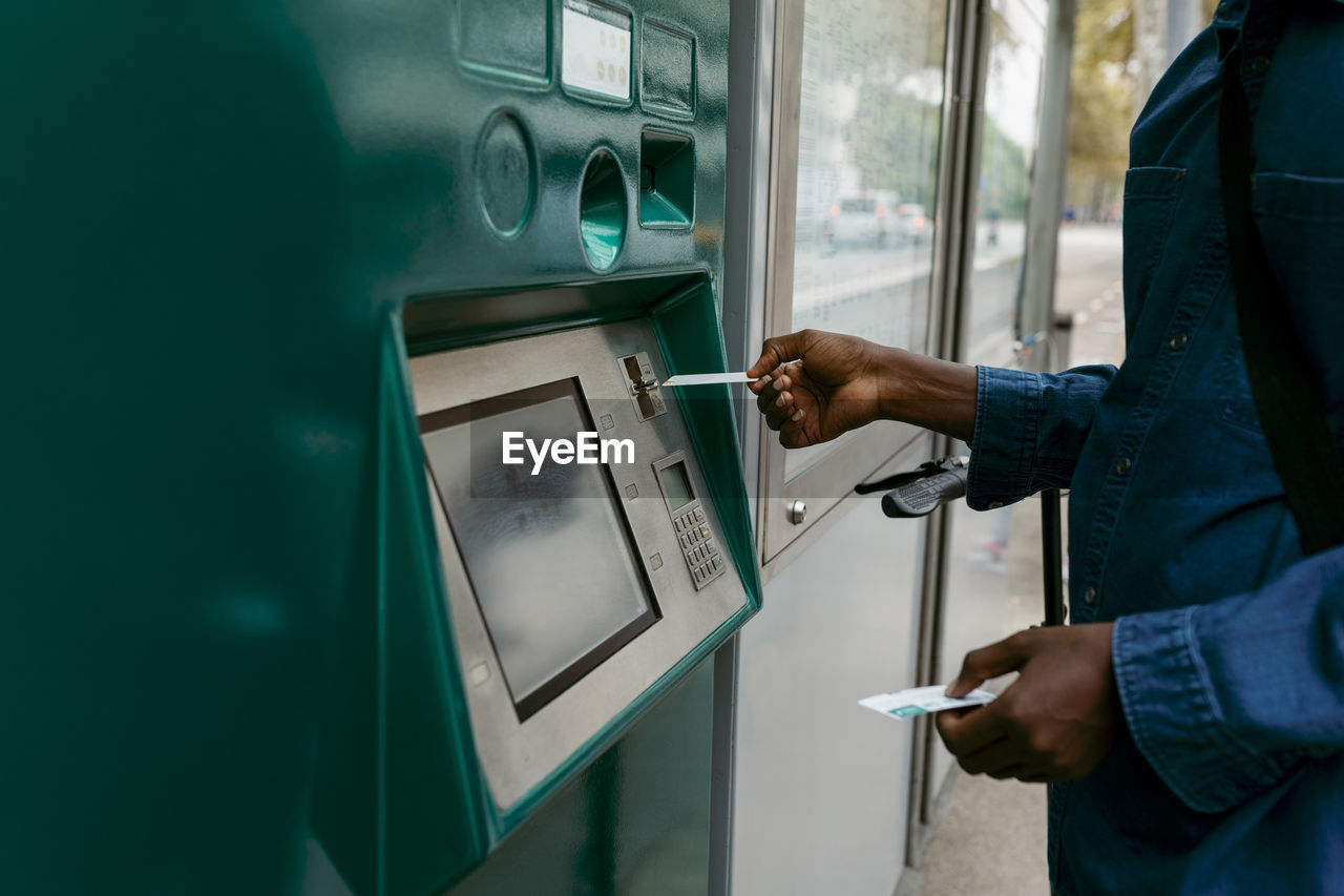 Businessman buying ticket while inserting credit card through machine