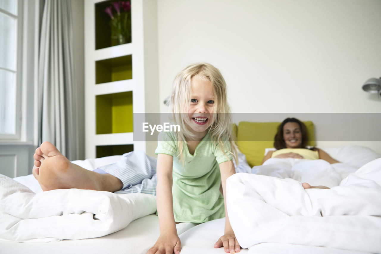Portrait of smiling little girl on hotel bed with her parents