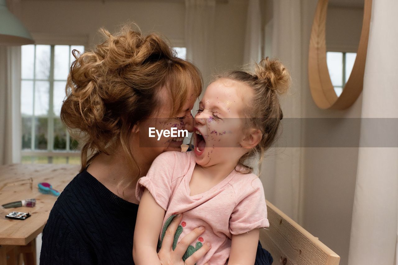 Mother an daughter having fun playing dress up with make up at home