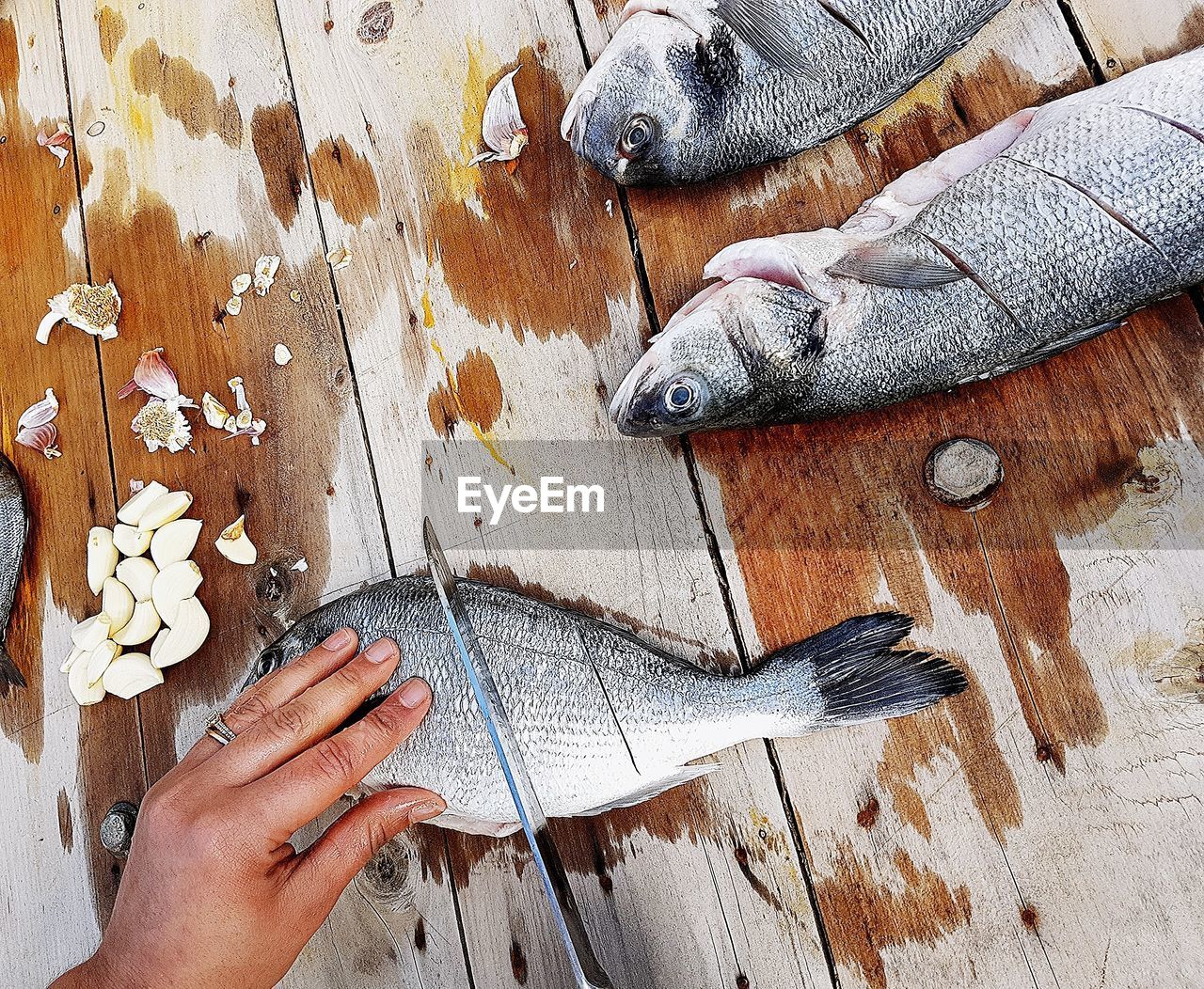 Cropped hand of woman chopping fish on wooden table