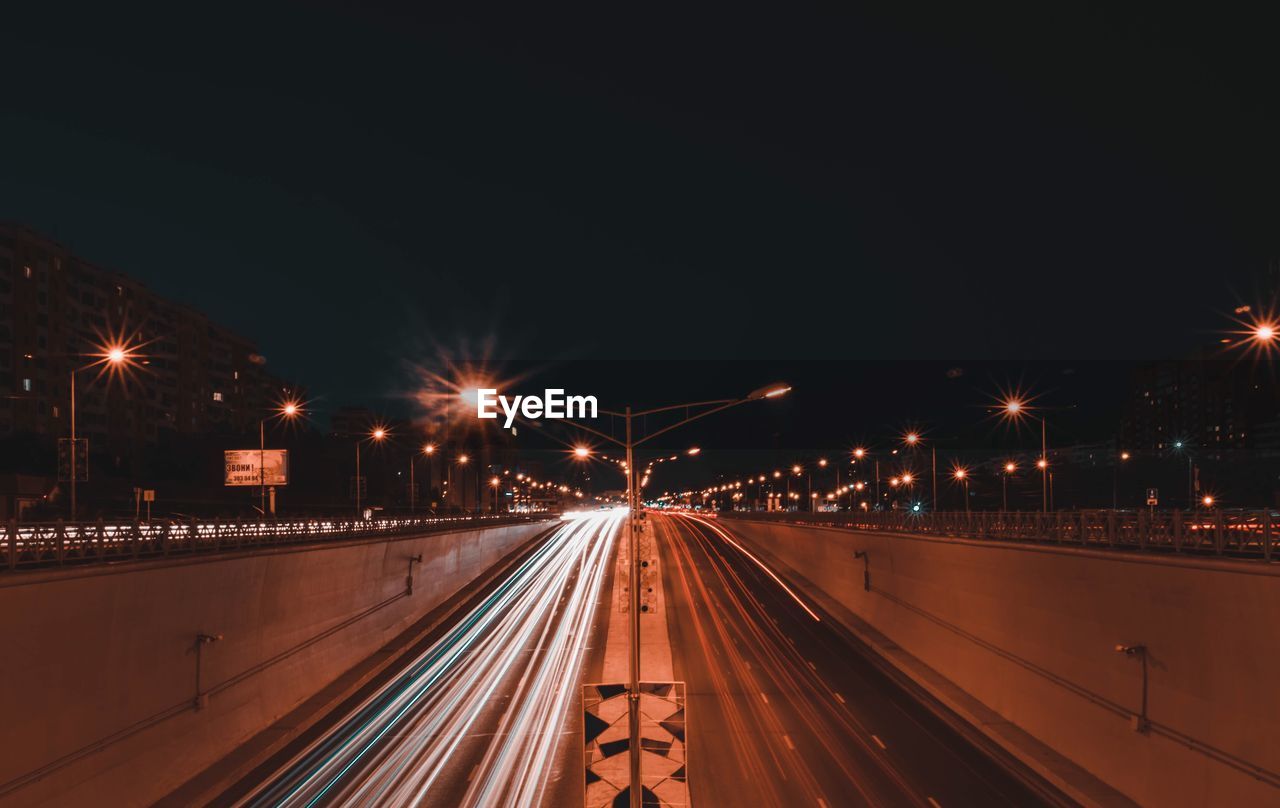 Light trails on road against sky at night