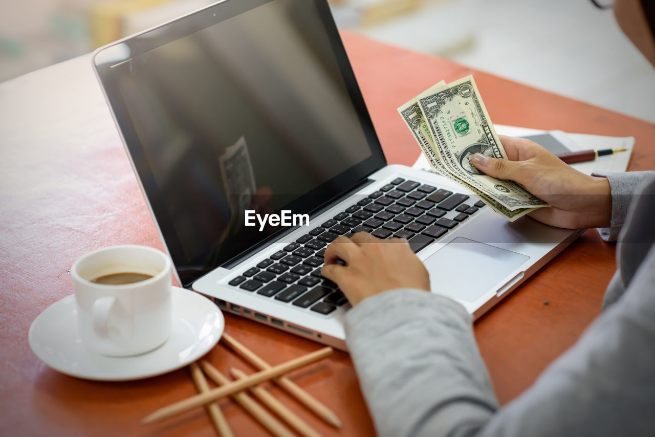 Midsection of businesswoman using laptop on table