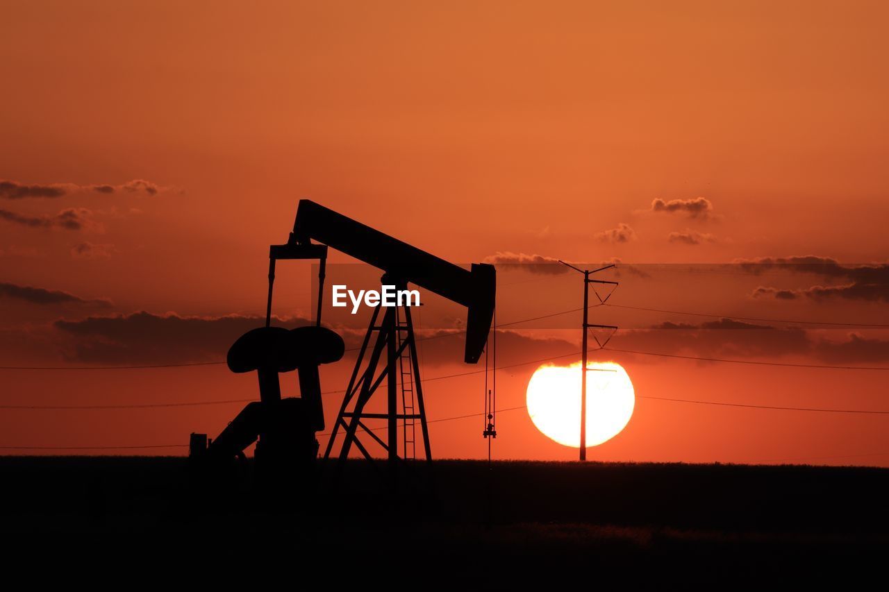 Orange sunset and pump jack silhouette in the texas oilfield