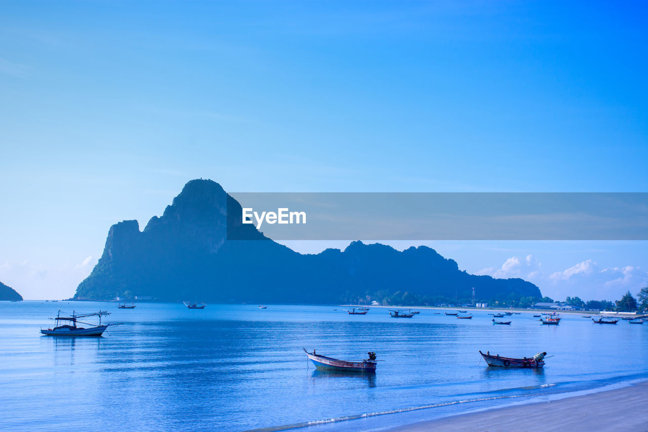 View of boats in sea against mountain