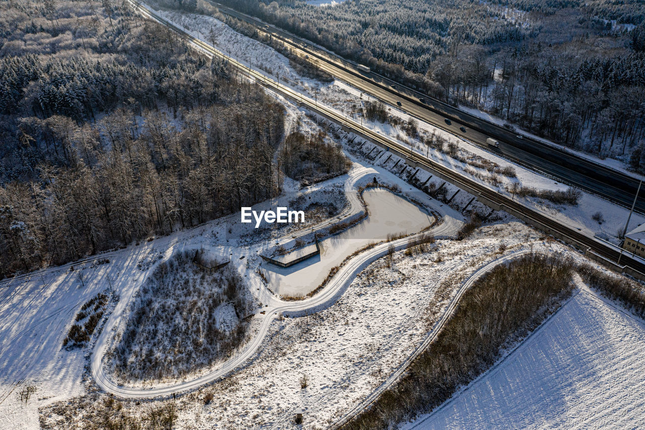 Aerial view of a frozen small pond near highway