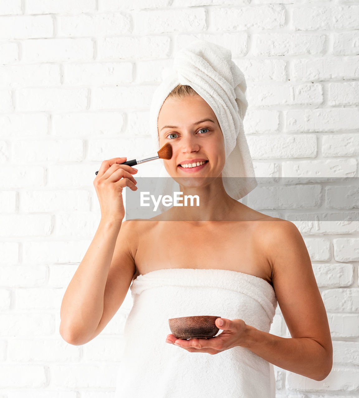 Beauty and wellness. young beautiful woman wearing white towels applying scrub on her face