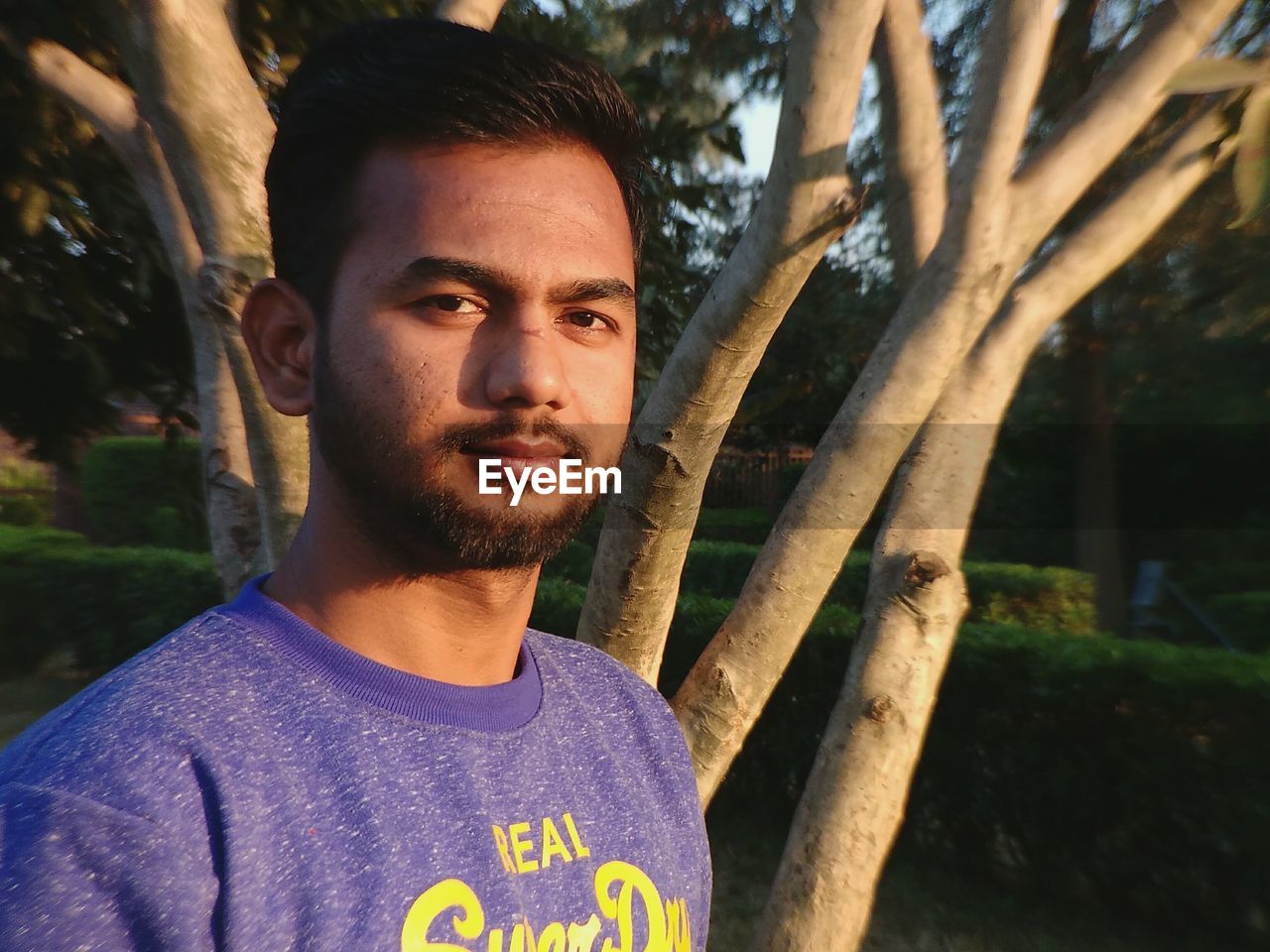 Close-up portrait of young man against tree