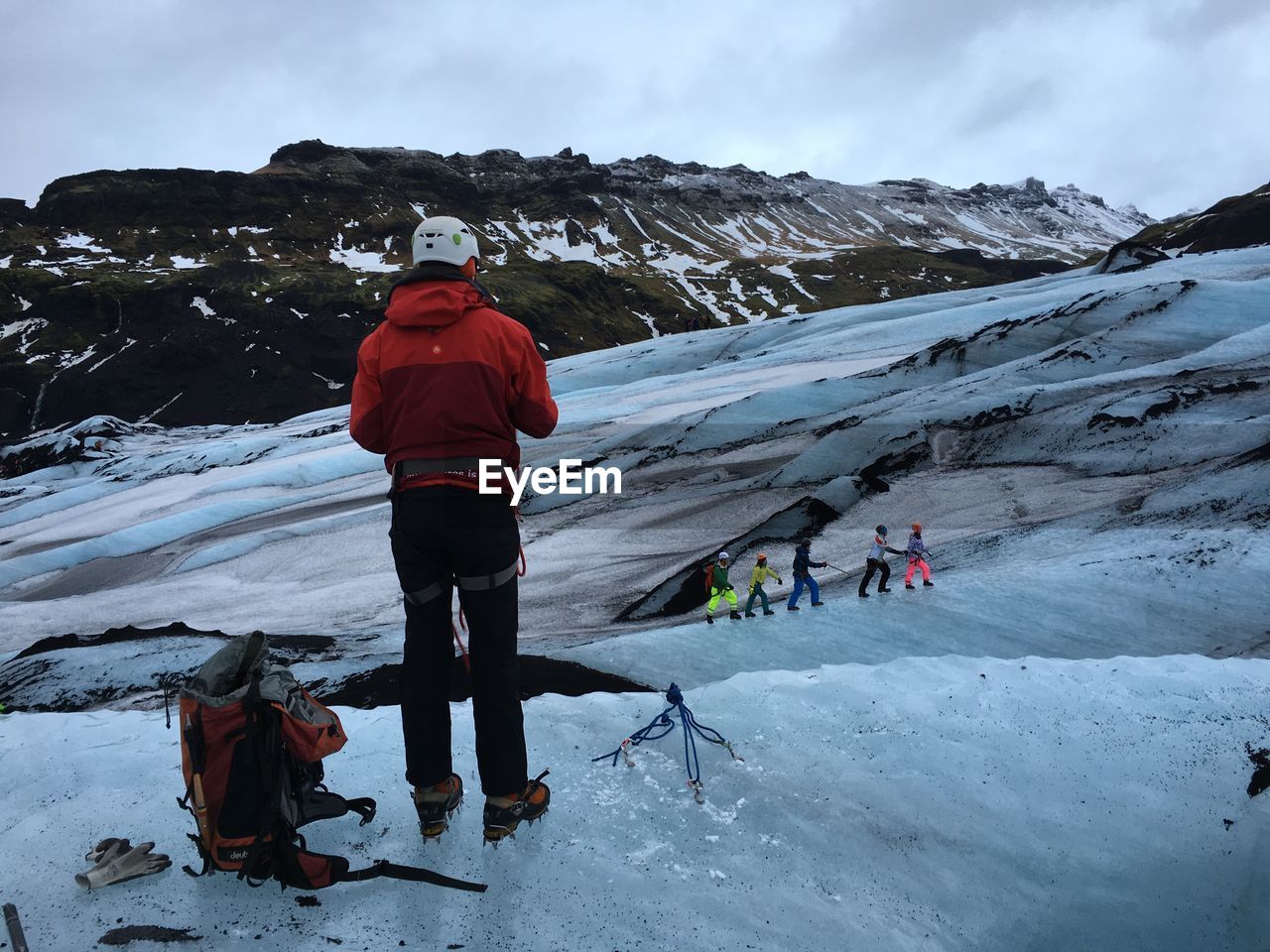 Rear view of hiker standing on snowcapped mountain against sky